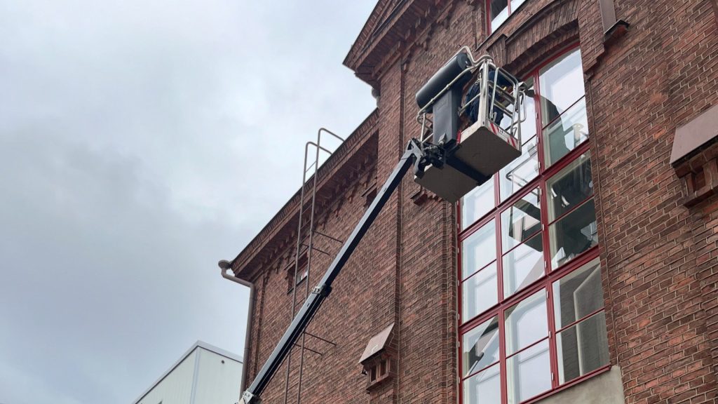 Ikkunoiden pesu nostokorista korkeaan rakennukseen Vaasassa. Ammattilainen puhdistaa ulkopinnat turvallisesti.